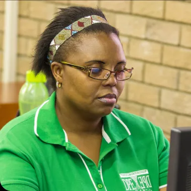 Woman wearing green and glasses reading a computer screen