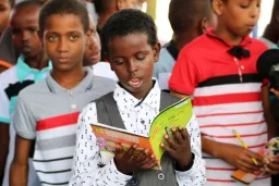 Children reading books and standing