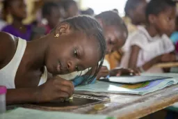 Child sitting in classroom writing in book