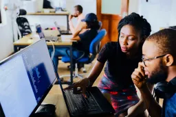 Man and woman at computer with lady pointing at screen