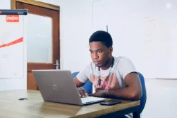 Male student working on laptop at desk