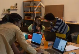 People working on laptops around a desk. Image licence: CC BY-SA