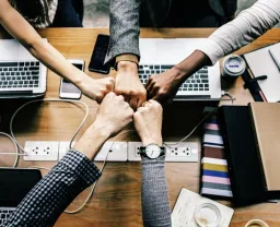 An image of hands of five people meeting at centre, illustrating the power of collaborative networking.