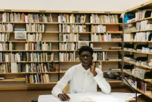 man sitting at desk with shelves of books behind him